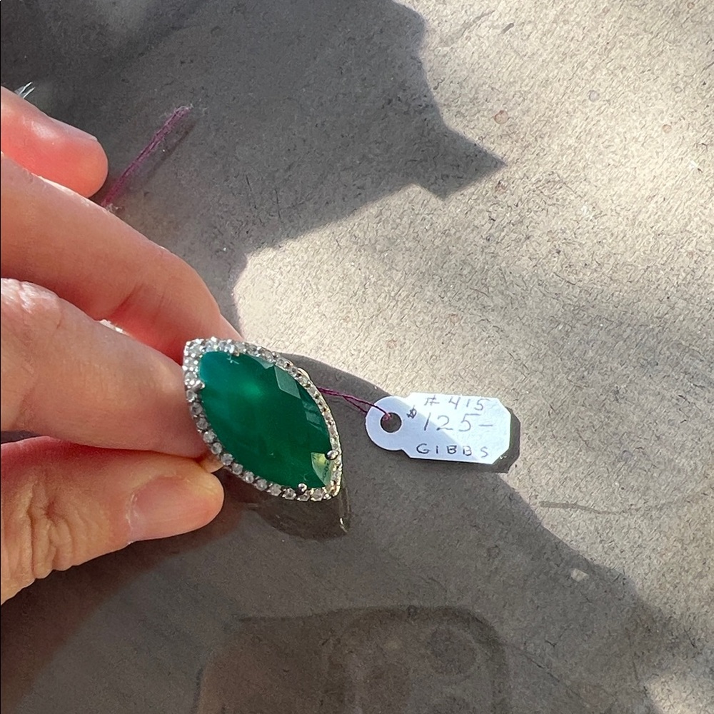 statement ring with a large emerald-green stone and halo setting.